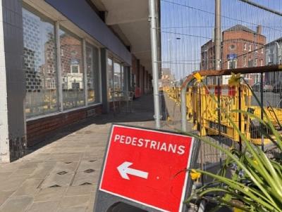 town centre construction A pedestrians sign pointing along the path next to fencing outside the former Hardshaw Centre